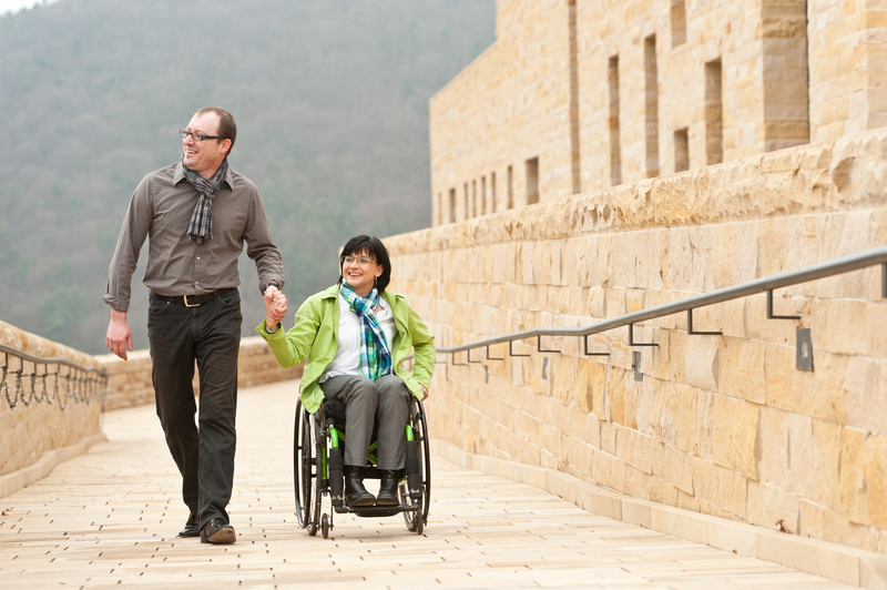 Rollstuhlfahrerin und Mann halten sich an den Händen auf einer Rampe des Hambacher Schlosses