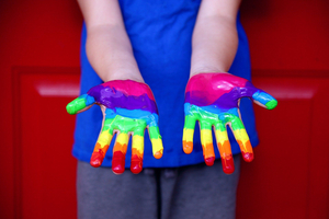 Kinderhände mit einem Regenbogen in bunter Farbe bemalt