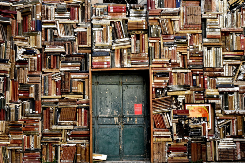 Alte Bücher stapeln sich in Regalen rund um eine Tür