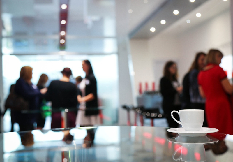 Tisch mit Kaffeetasse, im Hintergrund verschwommen Frauen in Businesskleidung
